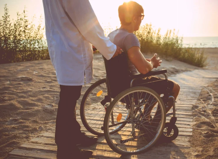padre con el hijo con discapacidad paseando en la playa
